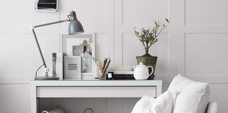 Smuk lys stue med daybed og konsolbord med billeder, lamper og en flot plante. Væggene er beklædt med høje skabslåger fra Ikea som gør det ud for høje paneler