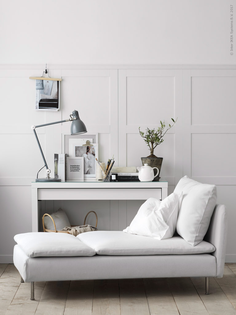 Smuk lys stue med daybed og konsolbord med billeder, lamper og en flot plante. Væggene er beklædt med høje skabslåger fra Ikea som gør det ud for høje paneler