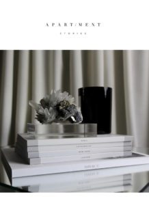 På billedet en stak bøger med et duftlys og en smuk krystal papirvægt, designet af svenske Apartment stories