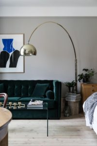 Stue med grøn velour sofa og art deco lampe i messing.