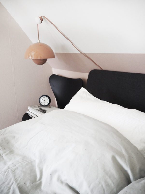 Soveværelse med rosa vægge, en Auping Essential seng med gråt hovegærde. PÅ væggen hænger en Flowerpot lampe i ferskenfarvet