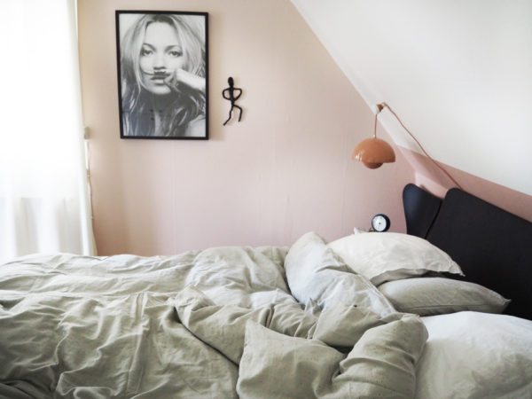 soveværelse med pudderfarvede vægge, fotokunst i sort/hvid på væggen og en lækker seng med gråt hovedgærde. Sengen hedder Essential og er fra Auping