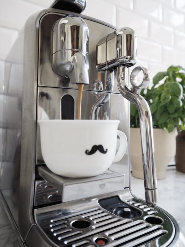 Kaffemaskine fra Nespresso der brygger kaffe i fin lille kop med overskæg