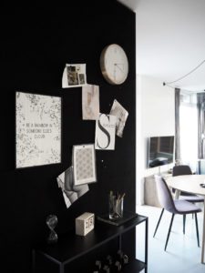 Et kig ind i en lejlighed, vi ser en sort væg med opslagstavle og et lille glimt af spisestuen