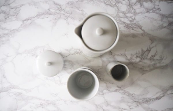 En opstilling på et bord fotograferet oppefra med Thermodan termokande, kopper, flødekande og sukkerskål fra Lyngbyporcelæn