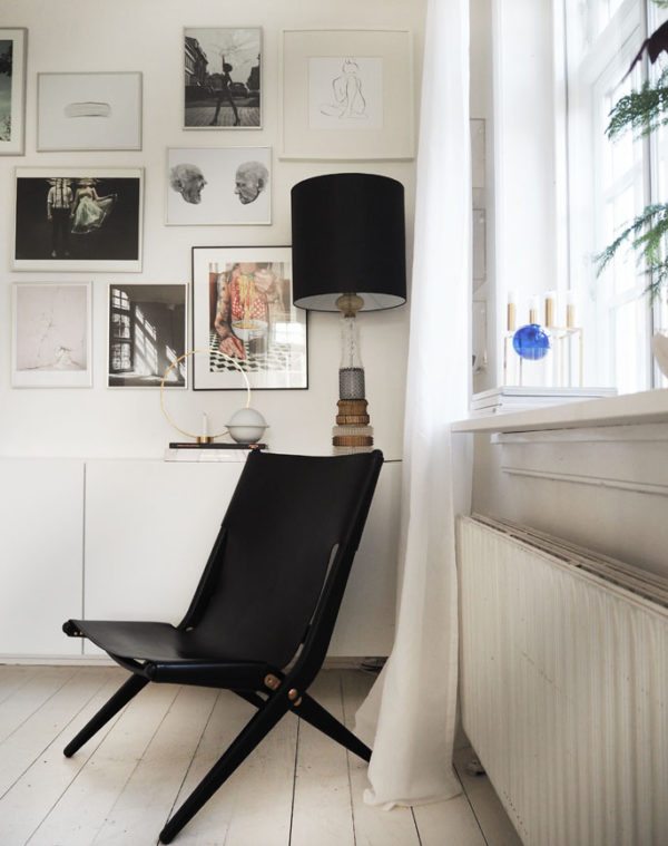 Saxe Lounge chair designet af Mogens Lassen i 1955. Her står den i et hjørne i en stue foran en kunstnerisk billevæg og en skænk med en stor krystallampe