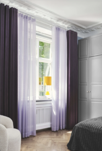 Gardiner der hænger dobbelt. Begge gardiner er lilla. Det tunge yderste gardin i velour er mørke lilla og de florlette inderste gardin er lyselilla.